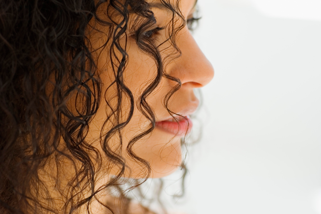 Close-up profile of a woman's damp, defined curls showing strand elasticity and condition
