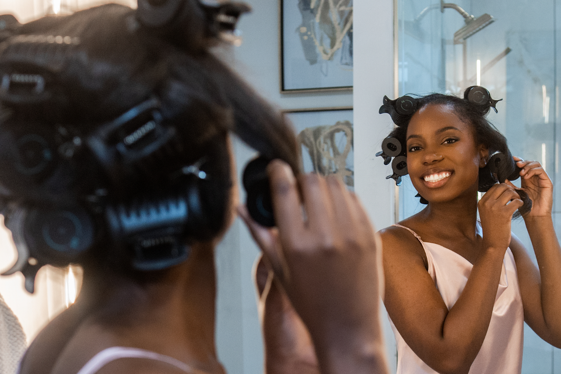Woman styling her hair with RevAir Amplifying Hot Rollers in multiple roller sizes