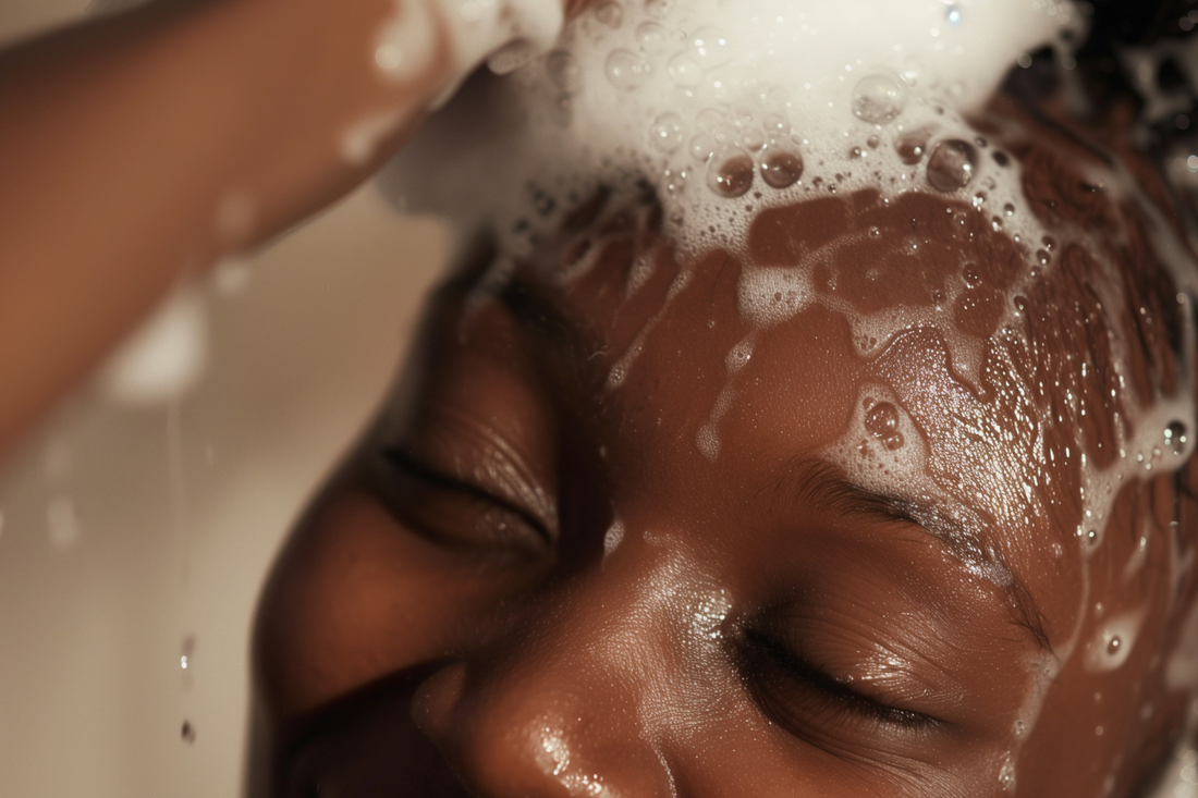 Close-up of a woman cleansing her scalp with shampoo, rich lather and water highlighting a healthy wash day routine for natural hair.