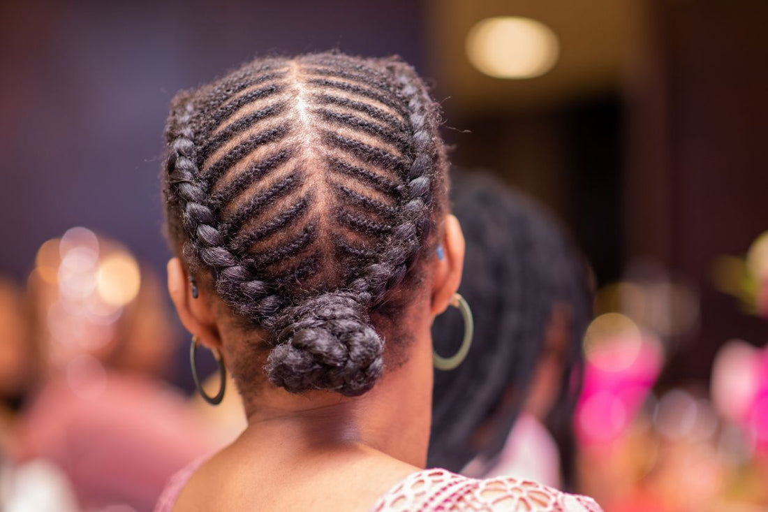 Close-up of a neatly braided cornrow protective style gathered into a low braided bun.