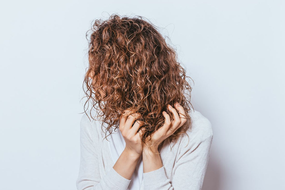 Person with damp curly hair holding their curls while troubleshooting curl definition and lasting hold.