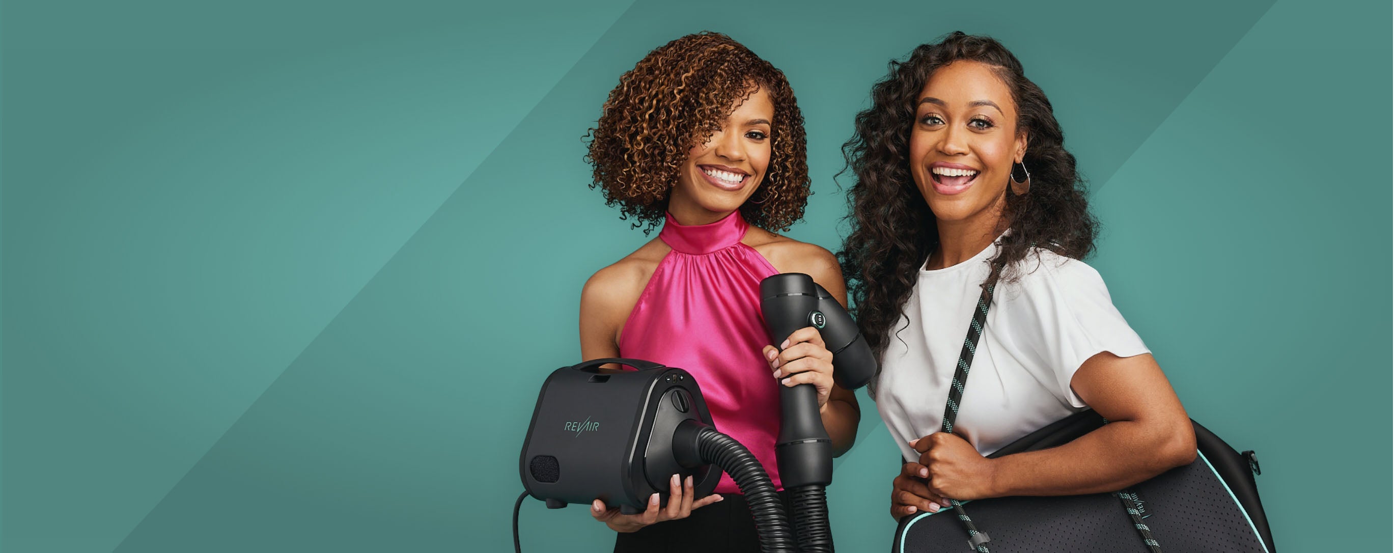 Two smiling women holding the RevAir reverse air hair dryer and weekender bag